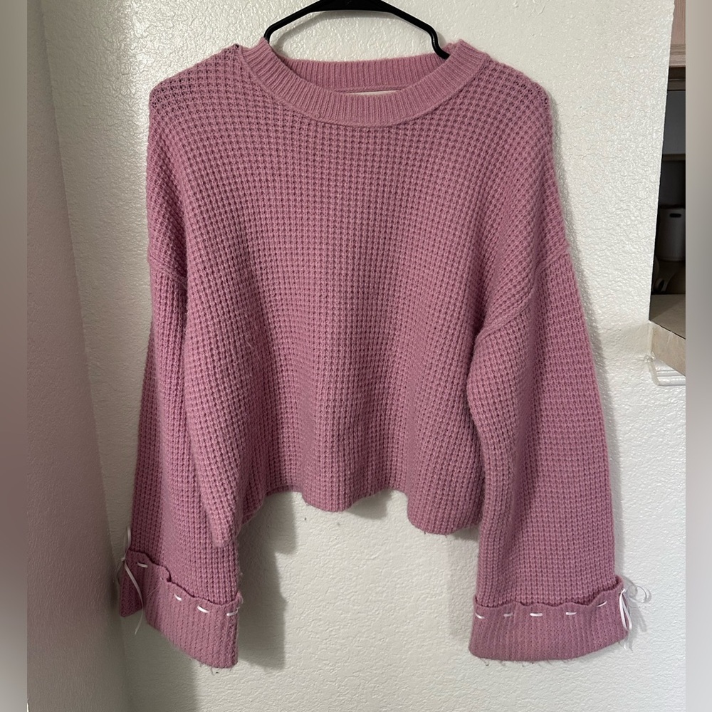 Woman’s pink sweater with bow sleeves
